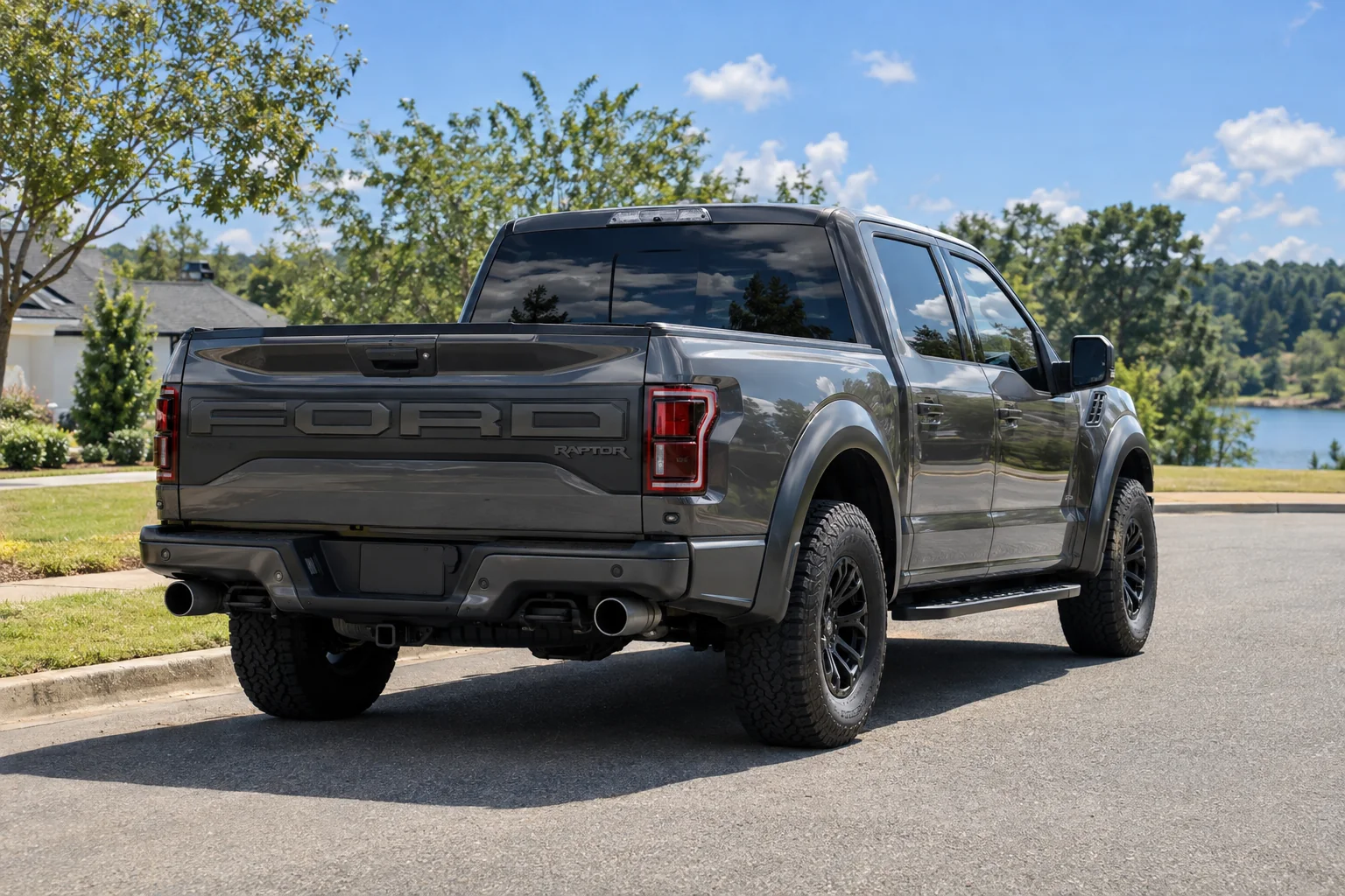 The dark tinted rear window and side glass of a gray pickup in the sun by an Alabama lake