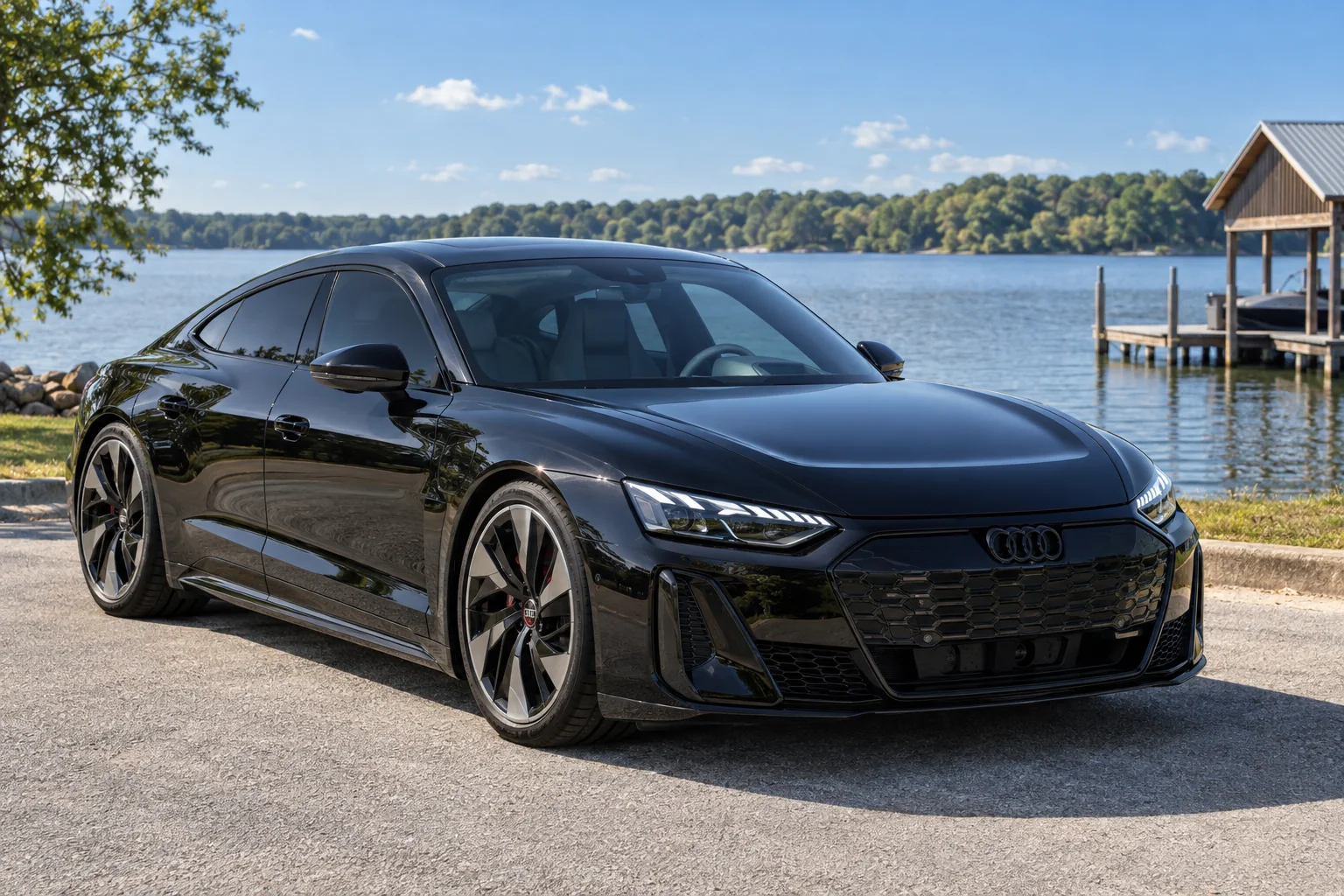 A black Audi RS e-tron GT with tinted windows parked by an Alabama lake