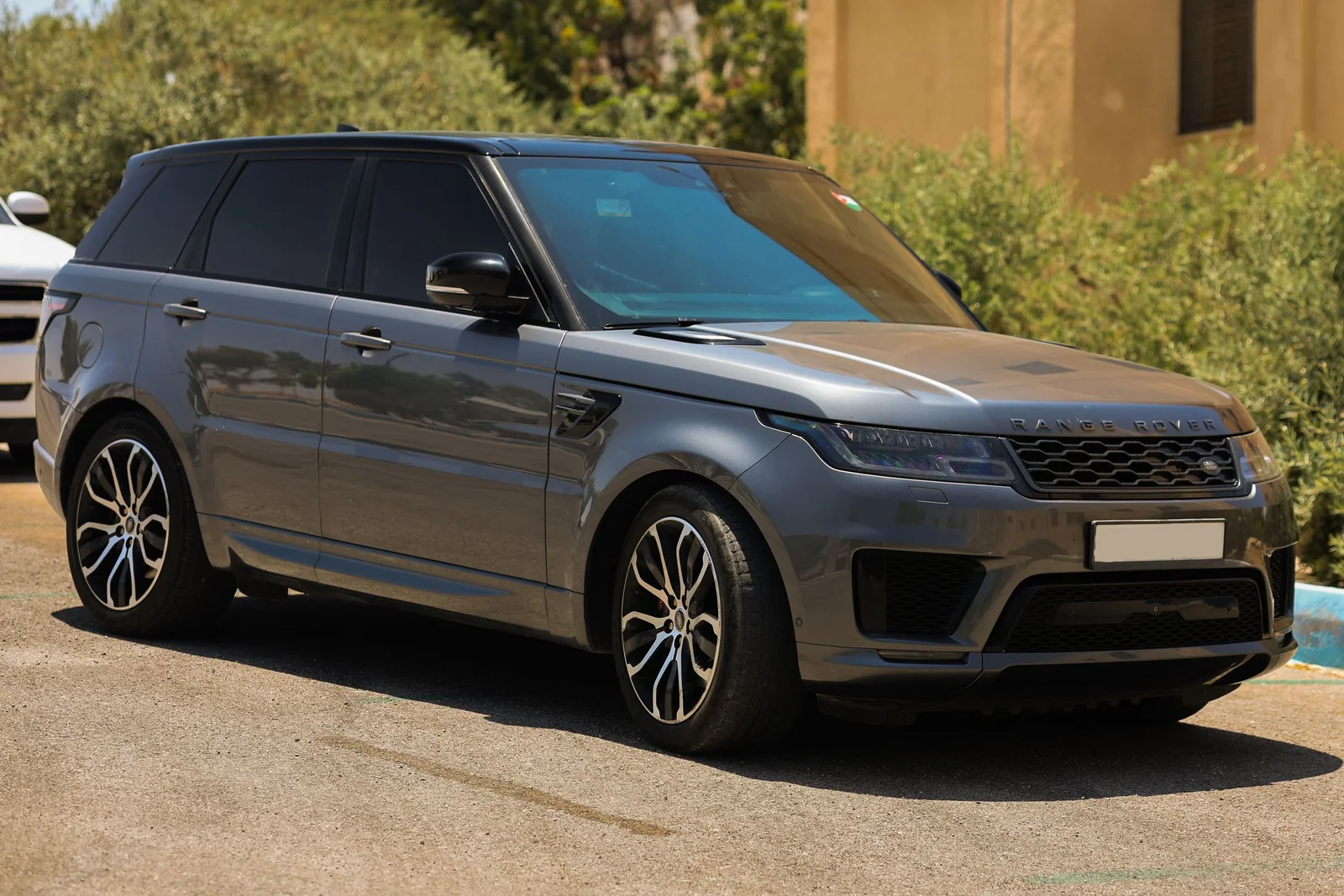 A gray SUV with dark tinted rear and side windows parked in the sun