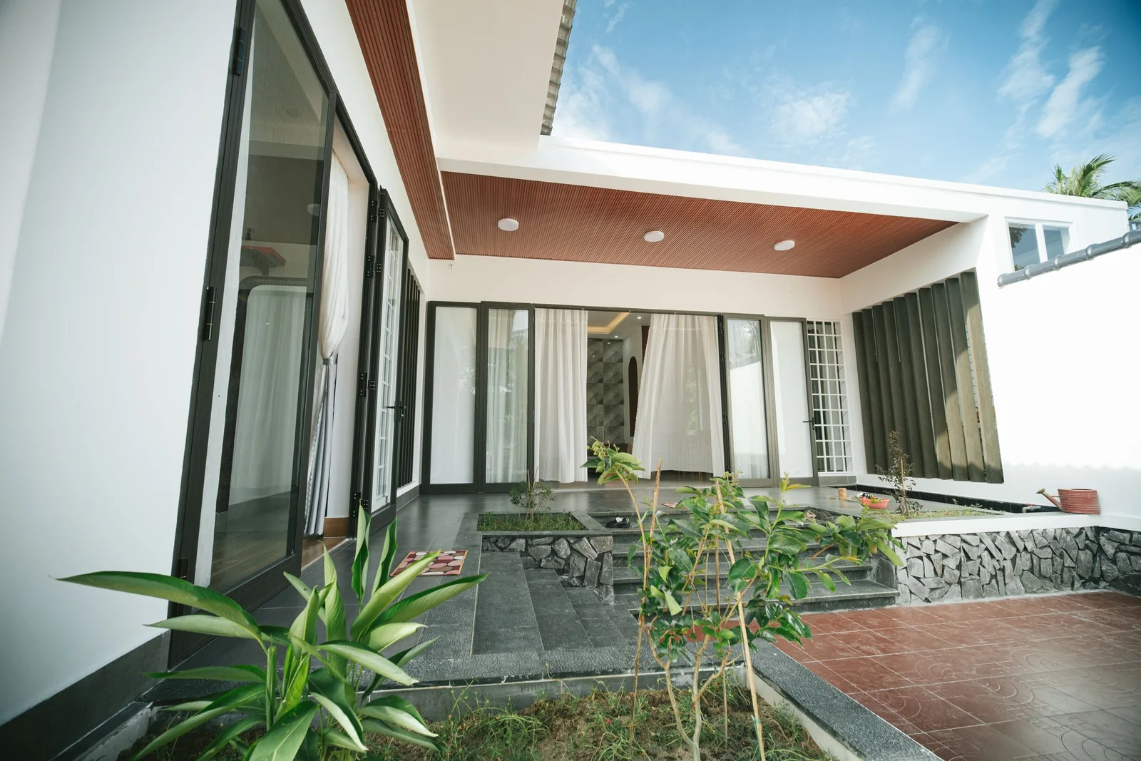 A modern home with walls of glass opening onto a garden
